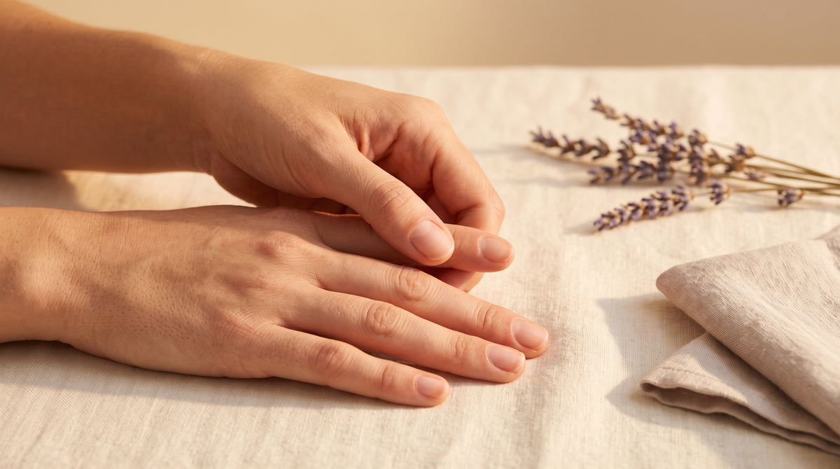 Mãos a massajar as unhas naturais sobre linho creme com lavanda seca